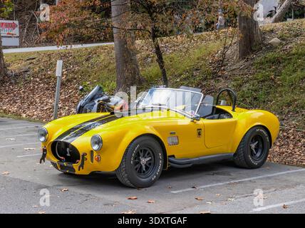 Deals Gap, Caroline du Nord, États-Unis - 18 octobre 2025 : un Shelby Cobra RReplica jaune parcs nid à une moto au bout de la queue du Dragon an Banque D'Images