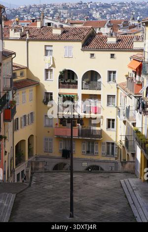 Toits du Vieux Nice avec des bâtiments jaunes, balcons voûtés et linge coloré suspendu dans Sunshine.Nice, France Banque D'Images
