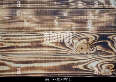 Vue de dessus rapprochée de planches en bois carbonisé avec un beau grain et des nœuds très contrastés. Surface en bois brun rustique idéale pour le design organique Banque D'Images