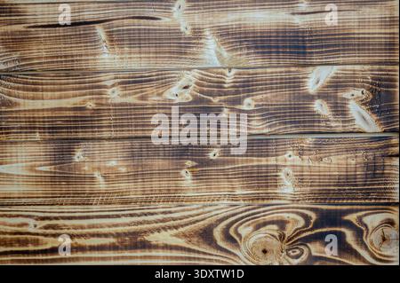 Vue de dessus rapprochée de planches en bois carbonisé avec un beau grain et des nœuds très contrastés. Surface en bois brun rustique idéale pour le design organique Banque D'Images