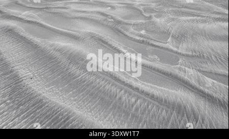 Un motif ondulé noir blanc de sable naturel, qui peut être utilisé comme image abstraite. Belles textures abstraites de sable Banque D'Images