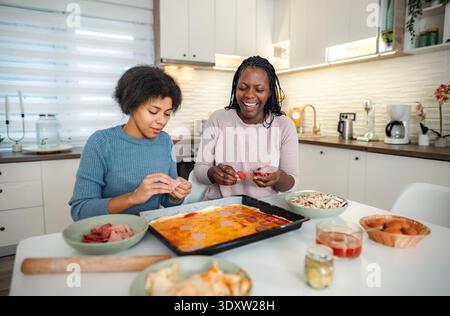 Fille mère afro-américaine faisant de la pizza maison dans la cuisine Banque D'Images