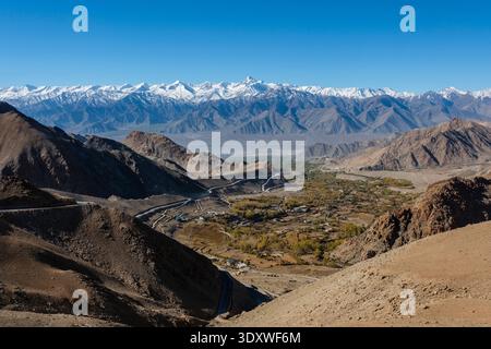 Une route de montagne sinueuse mène au village de Gonpa, Leh, tandis que le sommet enneigé de Stok Kangri domine l'horizon au loin. Banque D'Images