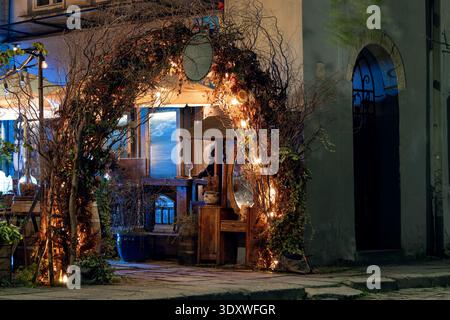 Une scène extérieure magique la nuit, avec une arche ornée de branches, de lumières de fées et de bougies, créant une ambiance romantique Banque D'Images