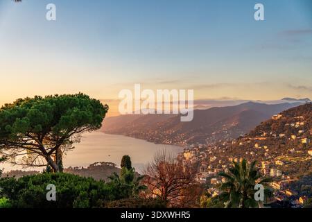 Une vue imprenable sur la côte italienne de la Riviera au coucher du soleil. Le plan capture les collines accidentées parsemées de maisons, un parapluie proéminent Banque D'Images