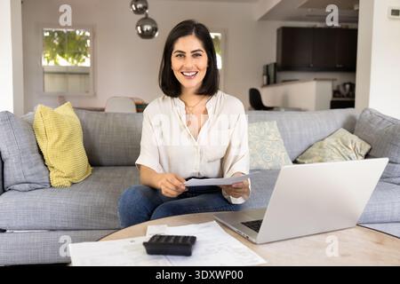 Heureuse jeune femme hispanique travaillant sur les finances personnelles Banque D'Images