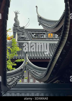 Architecture traditionnelle chinoise de temple avec toits en bois courbés et sculptures ornées, bâtiment historique dans une lumière dorée chaude. Banque D'Images