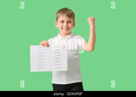 Écolier heureux avec de bons résultats de test scolaire sur fond vert Banque D'Images