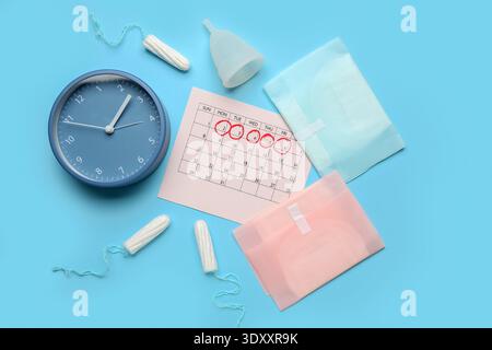 Composition avec calendrier menstruel, différents produits d'hygiène féminine et réveil sur fond de couleur Banque D'Images