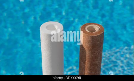 Deux cartouches de filtre à eau, une propre et une sale, sur fond de piscine. Banque D'Images