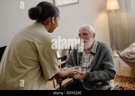 Femme noire aidant homme caucasien senior handicapé Banque D'Images