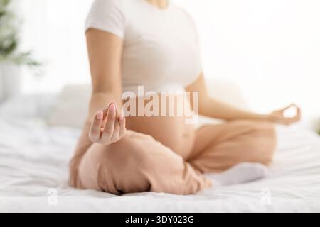 Gros plan d'une femme enceinte méditant par geste de la main au cours de la pratique prénatale du yoga Banque D'Images