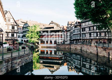Bâtiments médiévaux à colombages et restaurant la Maison des Tanneurs reflétés dans le canal de la petite France, Strasbourg, France. Banque D'Images