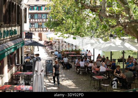 Restaurant au Pont du petit bois vert terrasse à Strasbourg, petite-France, bâtiments à colombages, parasols blancs, dîners au bord de l'Ill Banque D'Images