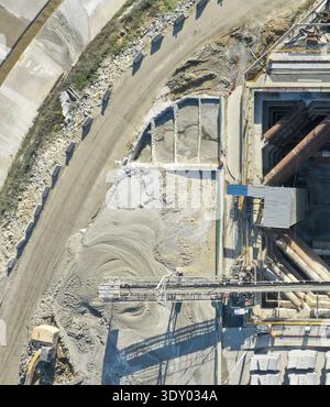 Vue aérienne d'un chantier de construction, avec des tas de sable et de gravier, de la machinerie lourde et des structures en béton montrant une scène d'actus industriels intenses Banque D'Images