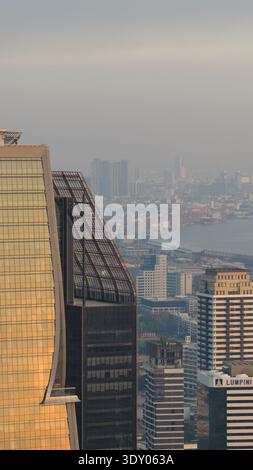 Vue aérienne de gratte-ciel traversant la ligne d'horizon brumeuse, reflétant la lumière dorée au milieu de la tapisserie urbaine, Bangkok, Bangkok, Thaïlande. Banque D'Images