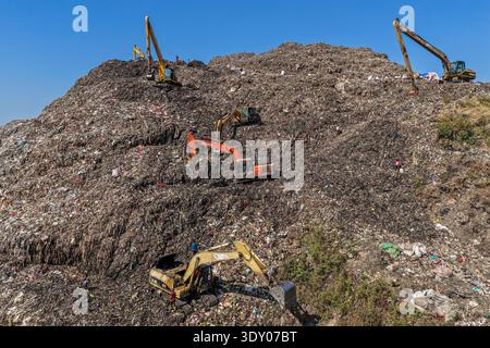 Chattogram, Bangladesh - 25 novembre 2025 : vue aérienne de la décharge d'Anondobazar où les excavatrices grippent à l'imposante montagne de déchets sous un s dégagé Banque D'Images