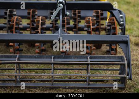 Gros plan des herses à disques et rouleaux métalliques extra-robustes sur un cultivateur moderne pour la préparation du sol. Machines agricoles prêtes pour les travaux de printemps dans les champs Banque D'Images