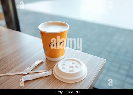 Café McCafe servi dans une tasse en papier de marque avec couvercle et sachets de sucre sur la table à l'intérieur du restaurant McDonalds. Concept de café à emporter et de restauration rapide Banque D'Images