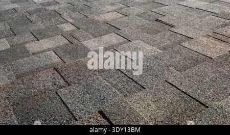 Texture de bardeaux de toit en asphalte sur le toit d'une maison résidentielle Banque D'Images