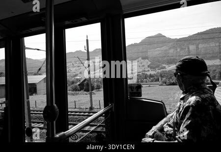 Noir et blanc, passager aîné regardant les champs alpins à travers une fenêtre de bus dans le canton de Schwyz Banque D'Images