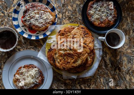 Un délicieux arrangement de diverses pâtisseries garnies de fromage, servies avec une tasse de café sur une table rustique. Parfait pour le petit déjeuner ou une collation. Banque D'Images