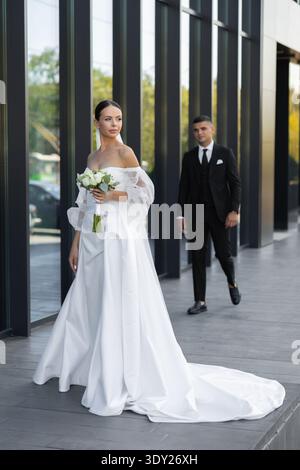 Couple de jeunes mariés célébrant leur mariage dans un cadre urbain, mettant en valeur l'amour et le bonheur lors de leur journée spéciale Banque D'Images