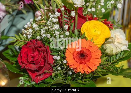 Bouquet floral lumineux avec rose rouge, gerbera orange et ranoncule jaune. Fleurs fraîches disposées en composition décorative. Banque D'Images