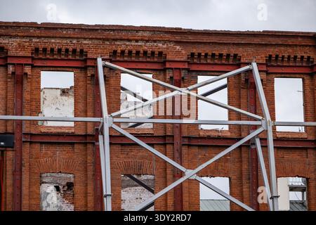 Façade de bâtiment en briques délabrée en cours de restauration avec contreventement en acier Banque D'Images