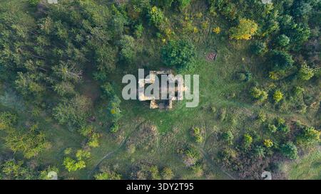 Vue aérienne de la chapelle de l'exaltation des ruines de la Sainte Croix à Bristev. Une végétation luxuriante entoure la structure en pierre, mêlant histoire et paysage naturel. Banque D'Images