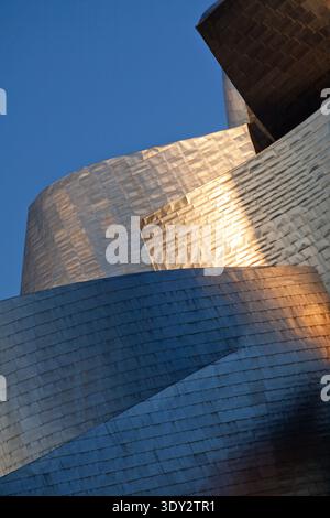 Lumière chaude du soir se reflétant sur les panneaux de titane incurvés du Musée Guggenheim Bilbao, Espagne. Banque D'Images