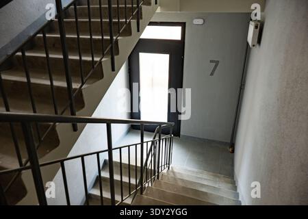Escalier en béton menant à la porte numéro sept dans un couloir d'appartement Banque D'Images
