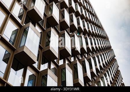 Façade de bâtiment moderne au design géométrique avec fenêtres carrées répétitives et reflets du ciel Banque D'Images