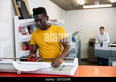 Portrait d'un employé positif de la maison d'impression avec des projets entre les mains Banque D'Images