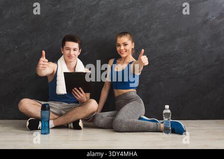 Jeune couple montrant les pouces vers le haut discutant du plan d'entraînement Banque D'Images