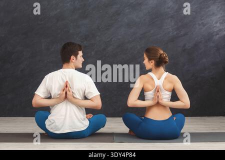Jeune couple en cours de yoga, étirement du dos Banque D'Images