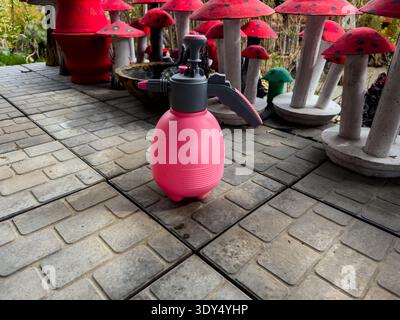 Pulvérisateur de jardin à pompe à main rose sur carreaux de patio Banque D'Images