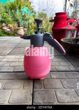 Outil de pulvérisation d'eau de jardin en plastique rose sur les carreaux de patio Banque D'Images