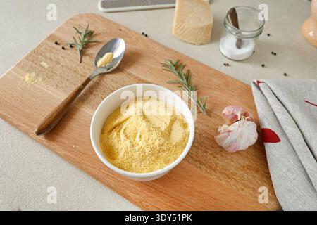 Farine de maïs dans un bol en céramique blanche sur une planche à découper en bois dans la cuisine. Parmesan et romarin. Ingrédients pour polenta. Cuisine italienne traditionnelle. Banque D'Images