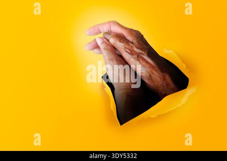 Les plus jeunes se tiennent la main avec les femmes plus âgées, à travers le trou dans le fond de papier jaune. Art contemporain minimaliste du collage Banque D'Images