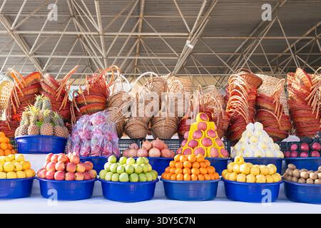 Étal de marché aux fruits en plein air animé avec des piles colorées de grenades fraîches, pommes, oranges, ananas dans des bols et des piles de paniers en osier. Samar Banque D'Images