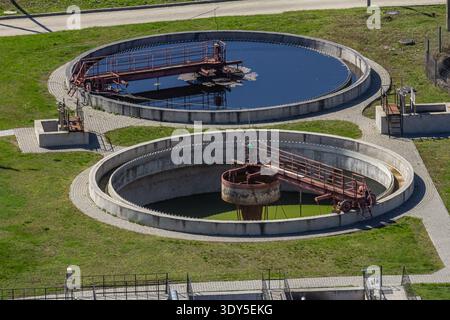 Deux grands réservoirs circulaires de purification d'eau sont visibles avec des machines positionnées dans chacun. L'établissement est situé dans un paysage verdoyant sous condit ensoleillé Banque D'Images