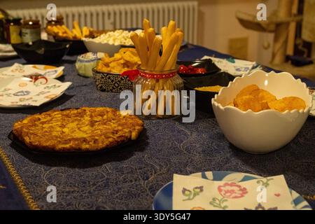Table à manger avec une nappe bleue, sur la table il y a divers apéritifs tels que des tortillas, des frites et des gressins Banque D'Images