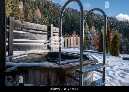 Bain à remous en bois sur terrasse enneigée dans les Dolomites, au nord de l'Italie Banque D'Images