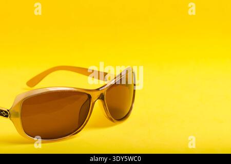 Gros plan sur les lunettes de soleil teintées ambré prises en studio, mettant l'accent sur les détails de la monture et de l'objectif Banque D'Images