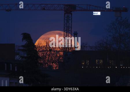 La lune se lève derrière une grue de chantier dans la soirée. La pleine lune en mars est aussi appelée lune vers car elle nous rappelle que le gel est SAF Banque D'Images