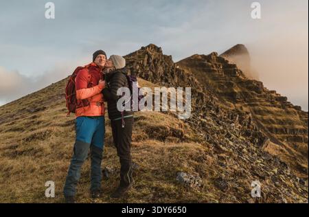 Jeune femme embrasse petit ami sur la joue lors d'une randonnée en Islande Banque D'Images