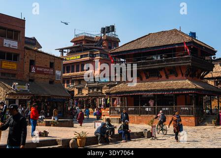 Touristes et habitants explorent les temples en bois et les boutiques de la place Bhaktapur Taumadhi par une journée ensoleillée au Népal Banque D'Images