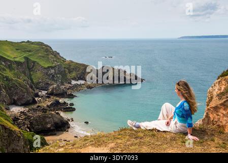 Jeune femme profite de la vue depuis un promontoire à la Coupe sur l'île de Sark dans les îles Anglo-Normandes Banque D'Images