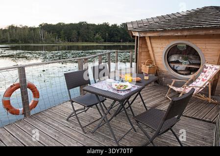 Dégustez un repas à l'extérieur de la cabine flottante du Clos de la Loutre à l'étang de Bornacq en France lors d'une soirée tranquille Banque D'Images